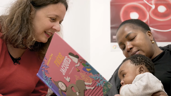 Une dame lit un album à un bébé et sa maman