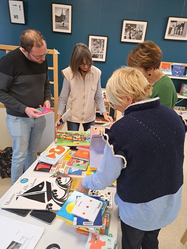 Adultes debout autour d'une table pleine de livres