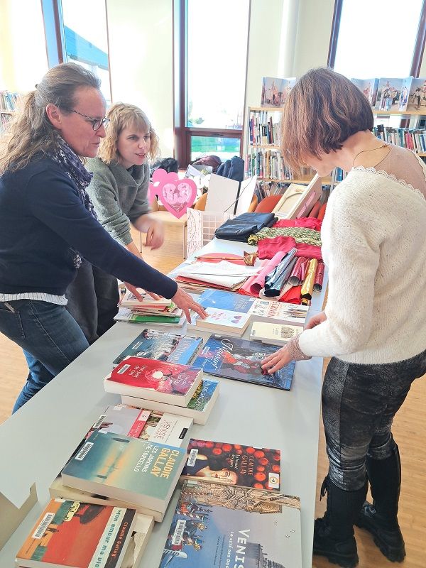 Trois personnes mettent en place des livres sur une table 