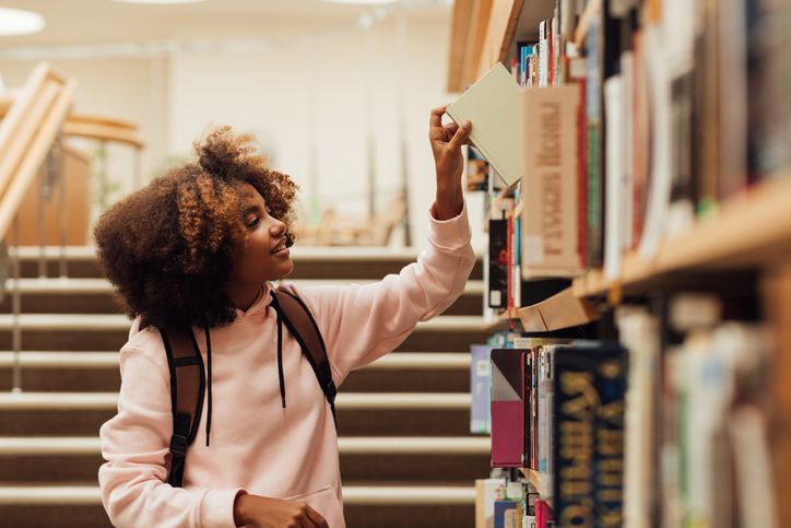 Fille prenant un livre de la bibliothèque dans la bibliothèque